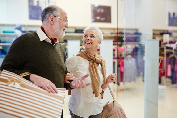 Senior spouses with paperbags talking while shopping in the mall