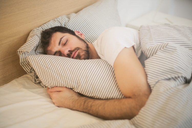 Persona descansando en una habitación oscura para mantener hábitos de sueño saludables y prevenir enfermedades comunes.